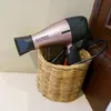 A rose gold and black hairdryer is placed inside a woven basket. Produktbild-Vorschau