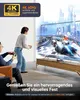 Two people playing a video game on a large TV, with a laptop and docking station visible on the TV stand. Produktbild-Vorschau