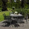A garden dining set with a round table and six chairs is set up on a paved patio surrounded by lush greenery. Produktbild-Vorschau