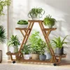 A wooden plant stand filled with various potted plants, placed indoors near a wall with sunlight casting shadows. Produktbild-Vorschau