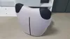 A unique, modern armchair with a distinctive shape, placed on a light-colored floor in a room with white furniture in the background. Produktbild-Vorschau