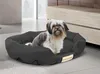 A dog is resting in a black dog bed in a room. Anteprima dell’immagine prodotto