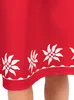 A close-up view of the hem of a red dress with a white floral pattern. Produktbild-Vorschau