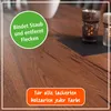 A close-up of a wooden table surface with decorative elements and text overlays. Produktbild-Vorschau