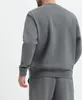 A person wearing a dark gray Nike pullover and matching pants, shown from the back against a white background. Produktbild-Vorschau