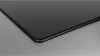 A close-up shot of the corner of a black glass stovetop on a brushed metal surface. Produktbild-Vorschau