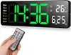 A hand holding a remote control is in the foreground, with a digital wall clock displaying the time, date, and temperature in the background. Produktbild-Vorschau