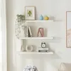Three white floating shelves mounted on a white wall, decorated with various items. Produktbild-Vorschau