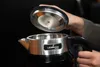 A person is holding the lid of a black and silver electric kettle. Podgląd zdjęcia produktu