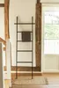 A towel ladder with a towel draped over it, placed on a wooden floor next to a doorway and a staircase. Anteprima dell’immagine prodotto