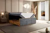 A bedroom with a bed that has its storage compartment open, revealing a mattress and the storage space below. The room has a modern, elegant design with a large window showing an autumn landscape. Produktbild-Vorschau