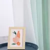 A framed picture with abstract art sits on a dark blue tray in front of a gradient sheer curtain. Produktbild-Vorschau