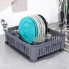 A dish drying rack with plates, glasses, and cutlery near a kitchen sink. Produktbild-Vorschau