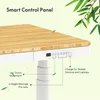 Close-up of a standing desk's control panel and tabletop, with bamboo texture and green foliage in the background. Produktbild-Vorschau