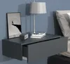 A modern, wall-mounted nightstand with an open drawer, displaying a framed picture, a clock, and a lamp. Podgląd zdjęcia produktu