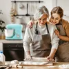 Two women are in a kitchen, one older and one younger, baking together. The younger woman has her arm around the older woman's shoulders as they both look down at the dough on the counter. Podgląd zdjęcia produktu