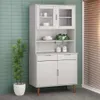 A white highboard cabinet with glass doors and wooden legs, placed against a light green tiled wall.