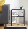 A black side table next to a gray sofa with a yellow pillow. Produktbild-Vorschau