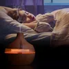 A person sleeping in bed with an essential oil diffuser emitting steam nearby. Anteprima dell’immagine prodotto