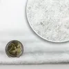 A close-up shot of a white filter material next to a 2 Euro coin. Produktbild-Vorschau