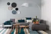 A modern living room with a sectional sofa, coffee tables, and decorative clocks on the wall. Náhľad obrázku produktu