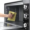 A hand is cleaning the inside of a toaster oven with a yellow sponge. Produktbild-Vorschau