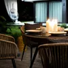 An outdoor dining set with chairs and a table set for a meal, illuminated by candles at night. Produktbild-Vorschau