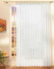 A sheer white curtain hangs in front of a doorway with a view of a sunset through the glass panes. A small table with a plant and a teapot is visible to the left. Produktbild-Vorschau