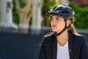 A woman wearing a black blazer and a black helmet is looking to the side. Produktbild-Vorschau