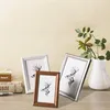 Three picture frames with deer illustrations are displayed on a wooden surface, with a vase and greenery in the background. Produktbild-Vorschau