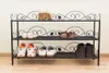 A black metal shoe rack with three shelves holding various shoes. Produktbild-Vorschau