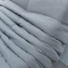 A close-up view of folded gray fabric, likely a sofa or blanket, showing its texture and stitching. Anteprima dell’immagine prodotto