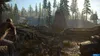 A scene from the video game Days Gone, showing a character in the foreground looking at a horde of zombies in a forest setting with a wooden structure in the background. Produktbild-Vorschau