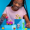 A young girl playing with Littlest Pet Shop toys, including animal figures and a vehicle, against a blue background. Náhľad obrázku produktu