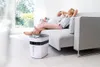 A couple relaxing on a couch with an air purifier in the foreground. Produktbild-Vorschau