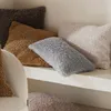 Several fluffy throw pillows are arranged on a textured shelf. Produktbild-Vorschau