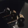 Three gold and black faucet handles with diamond-cut detailing are arranged on a reflective black surface, with dramatic lighting creating highlights and shadows. Podgląd zdjęcia produktu