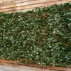 A close-up view of a green artificial ivy fence attached to a wooden slat wall. Voir les images du produit