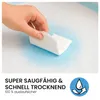 A hand is shown folding a white absorbent pad over a blue wet area on a larger pad, demonstrating absorbency. Produktbild-Vorschau
