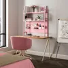 A pink desk with a matching chair and a pink shelf unit filled with office supplies and decor, set up in a bedroom next to a bed and a whiteboard. Voir les images du produit