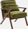 A green velvet armchair with wooden legs and a small pillow. Produktbild-Vorschau
