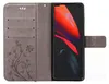 A flip-style phone case is open, showing the inside with card slots and an embossed floral pattern on the left, and a smartphone with a vibrant red and black abstract wallpaper on the right. Produktbild-Vorschau