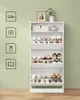 A white shoe cabinet filled with shoes, placed against a light green wall. Decorative items are on top of the cabinet. Produktbild-Vorschau