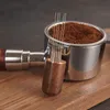 Close-up of an espresso distribution tool with needles and a portafilter filled with coffee grounds, resting on a wooden surface. Produktbild-Vorschau