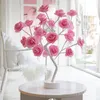 A decorative LED lamp shaped like a tree with pink roses, placed on a small table indoors. Produktbild-Vorschau