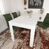 A white dining table with green chairs in a dining room setting. Produktbild-Vorschau