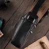 A black leather bag on a wooden surface with some map-like paper and rope. Podgląd zdjęcia produktu