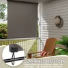 A balcony with a gray roller blind, a wooden chair, and a hat on the wall. Produktbild-Vorschau