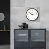 A modern living room with a wall clock and a cabinet. Voir les images du produit