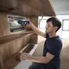 A man is working on an electrical panel, holding a Bosch cordless screwdriver. Voir les images du produit